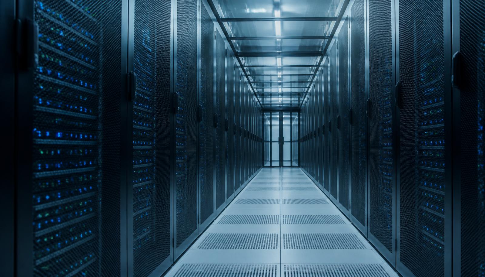 Cold aisle of a modern data center with rows of server racks lit by blue status indicators