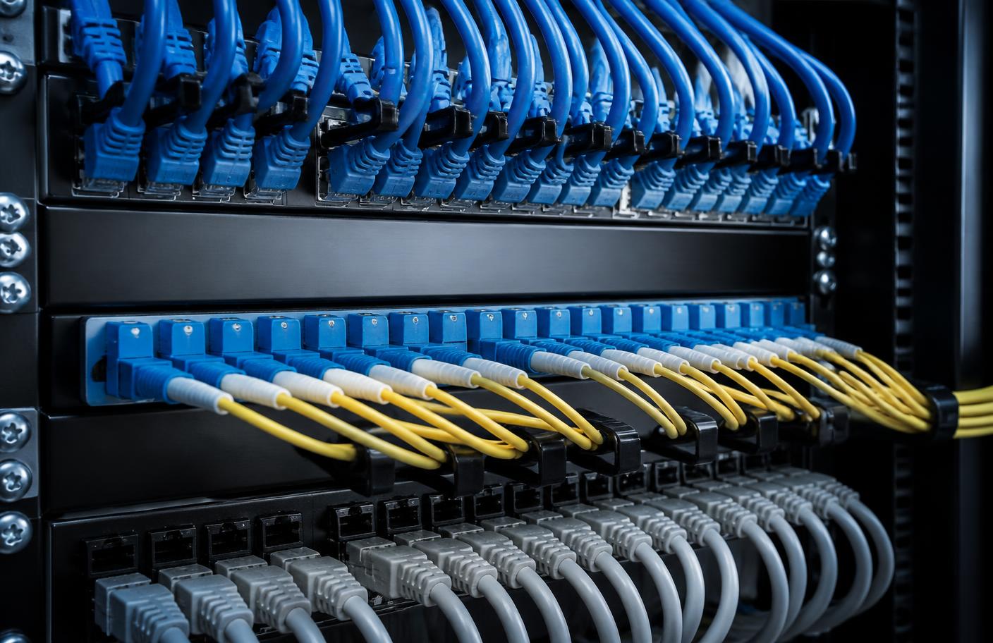Close-up of a structured patch panel with neatly routed blue, yellow and grey network cables